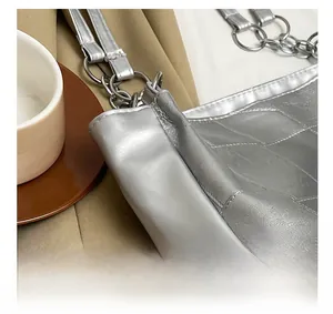 Close-up of silver tote bag featuring quilted texture and metallic chain ring hardware