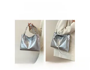 Detail of silver metallic tote bag featuring geometric texture and metal chain handle