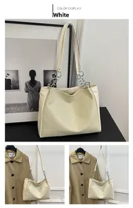 Close-up of cream white tote bag featuring geometric patchwork texture and silver chain strap