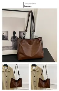 Detail of brown tote bag featuring irregular geometric embossed faux leather and chain strap