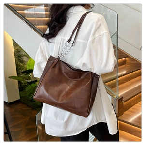 Λεπτομέρεια καφέ τσάντας tote patchwork με μεταλλική αλυσίδα που φοριέται στον ώμο