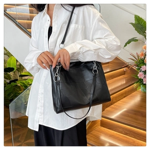Detail of geometric patchwork on black PU leather tote bag with silver ring hardware