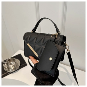 Detail of black quilted shoulder bag with gold metal trim and matching mini charm pouch