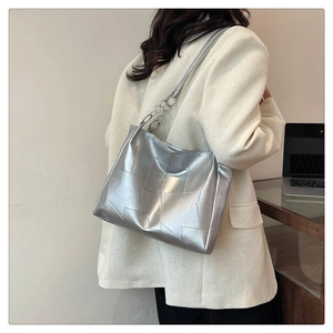Detail of silver metallic tote bag with geometric patchwork and shiny mirror finish