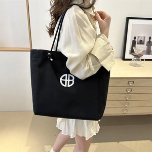 Bolso tote de lona negra con logo geométrico blanco en un entorno de hogar moderno
