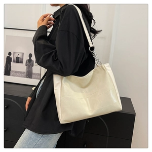 Detail of white tote bag with grid embossed texture and silver chain strap attachment