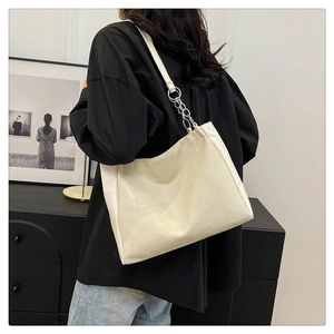 Detail view of cream textured tote bag featuring grid pattern and metal chain strap