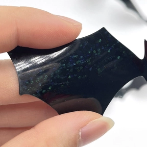 Macro detail of 3D bat wall sticker with blue-green glitter on a glossy black surface