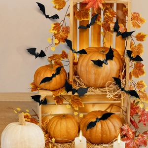 Detail of 3D black glitter bat stickers on a rustic Halloween pumpkin and maple leaf setup