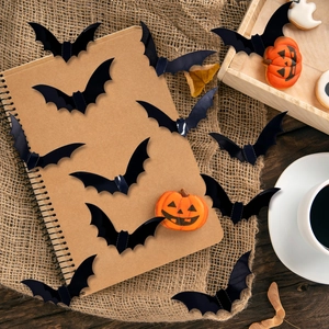 Set of 3D black bat wall stickers in various sizes for Halloween decor on a notebook
