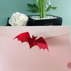 Detail of glittery red 3D bat sticker applied on a pearlescent pink envelope seal
