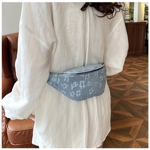 Detail of light blue floral embossed waist bag with zipper on a casual female model