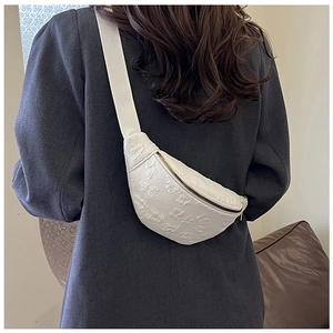 Detail of white embossed floral saddle bag with adjustable strap shown on model back