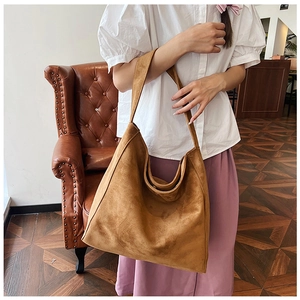 Close-up of caramel brown suede tote bag featuring a minimalist wide strap design