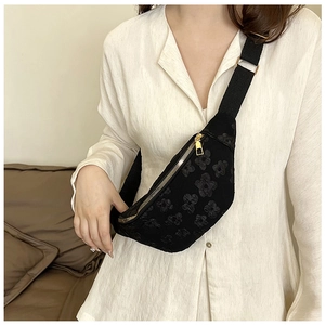 Détail du sac bandoulière noir texturé avec fermeture dorée et large sangle en tissu