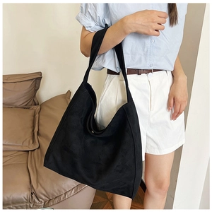 Detail of black suede tote bag showing soft texture and wide integrated shoulder strap