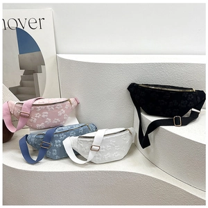 Detailed view of floral textured fabric crossbody bags in four pastel colors on a stand
