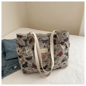 Detail of colorful butterfly embroidery on a white canvas tote bag with leather handles