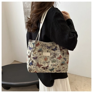 Detail of the colorful butterfly embroidery and leather patch on the beige tote bag
