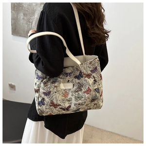 Detailed side view of a large tote bag with butterfly prints shown on a model