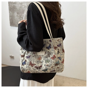 Close-up of tapestry tote bag featuring colorful butterfly embroidery and leather tag
