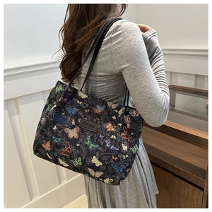 Detail of colorful butterfly jacquard tote bag with leather logo tag and shoulder straps