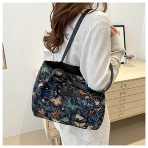 Close-up of butterfly embroidery pattern and black leather handle on a large tote bag