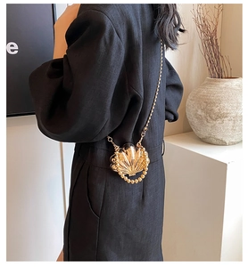 Detail of golden shell-shaped mini bag with bead edges and thin metal chain strap