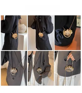 Detail of shell-shaped metal evening bag with pearl chain and radial texture details