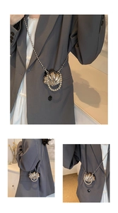 Detailed view of shell-shaped silver mini bag with pearl trim and silver bead chain