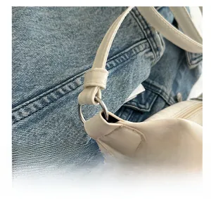 Détail de la boucle en métal argenté reliant la bandoulière en cuir blanc et le sac