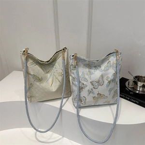 Artistic embroidered tote bags with bird and butterfly patterns on minimalist stands