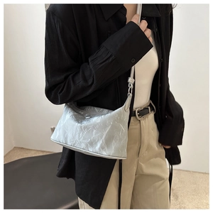 Sac hobo argenté à texture métallisée plissée porté à l'épaule pour démonstration