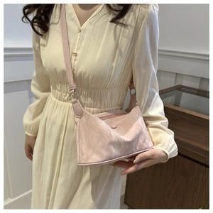 Sac à bandoulière rose plissé à texture métallique porté par un mannequin en intérieur