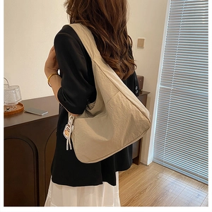 Détail d'un grand sac fourre-tout plissé beige avec un charme de dessin animé sur bois
