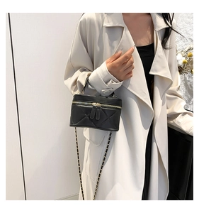 Close-up of quilted black leather phone bag with gold chain strap and dual zippers