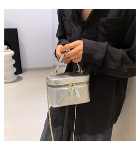 Detail view of silver quilted bucket bag with golden chain and metallic texture