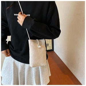 Close-up of light beige mini crossbody phone bag with elegant pearl clasp and thin strap