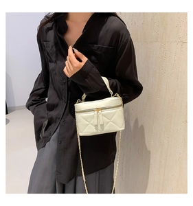 Close-up of beige quilted leather mini bag with gold chain strap and top handle