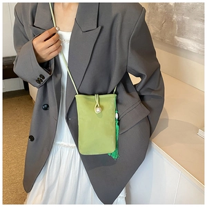 Chic borsa a tracolla verde per telefono con chiusura in perla e nappa in primo piano.