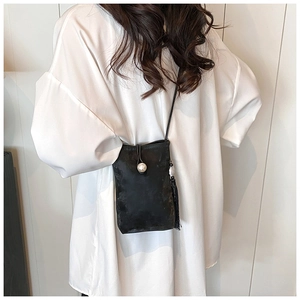 Minimalist black crossbody phone bag with pearl buckle and tassel on white shirt