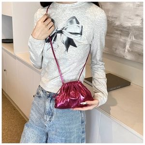 Detail view of the metallic pink ruched dumpling bag on a model showing mini size