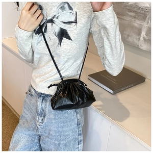 Détail d'un sac nuage plissé noir en similicuir brillant porté par un mannequin