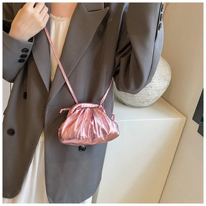 Close-up of pinkish purple metallic pouch bag with pleated texture on grey blazer