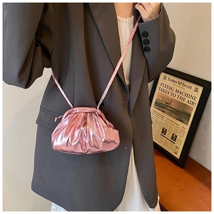 Close-up of metallic pink pleated shell bag with crossbody strap and cloud texture