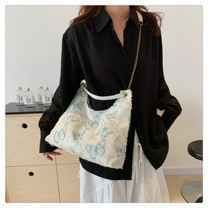 Dettaglio ricamo farfalla blu su borsa tote beige testurizzata con tracolla a catena