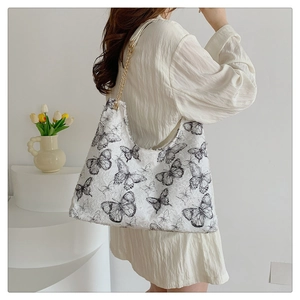 Détail d'un grand sac cabas en toile blanche avec imprimés papillons noirs et bandoulière chaîne