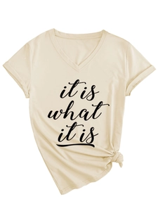 Détail du t-shirt beige à col en V avec texte 'it is what it is' et nœud sur le bas