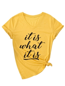 Détail du t-shirt jaune à col en V avec texte 'it is what it is' et ourlet noué stylé