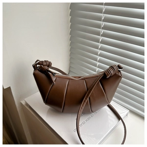 Detail of dark brown dumpling bag with pleated texture and side knot shoulder strap